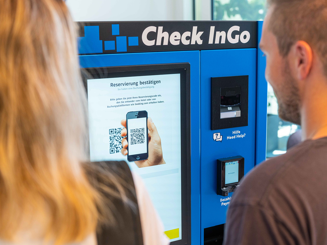 Guests scanning a QR code at a hotel check-in kiosk with Beetronics touchscreen for quick and contactless check-in.